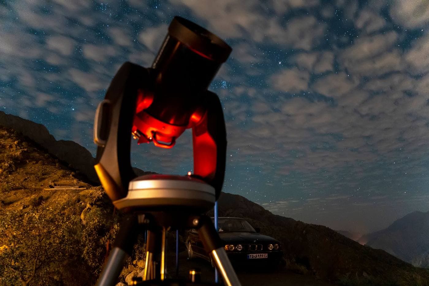 A telescope on a tripod silhouetted against a dense starry sky