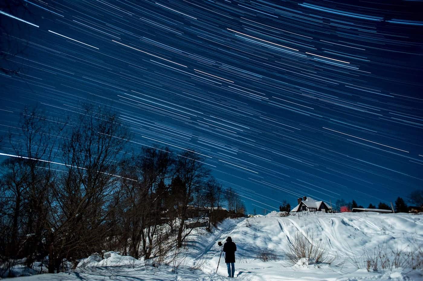 A long-exposure photograph showing star trails over a landscape, the effect a tracking mount exists to prevent