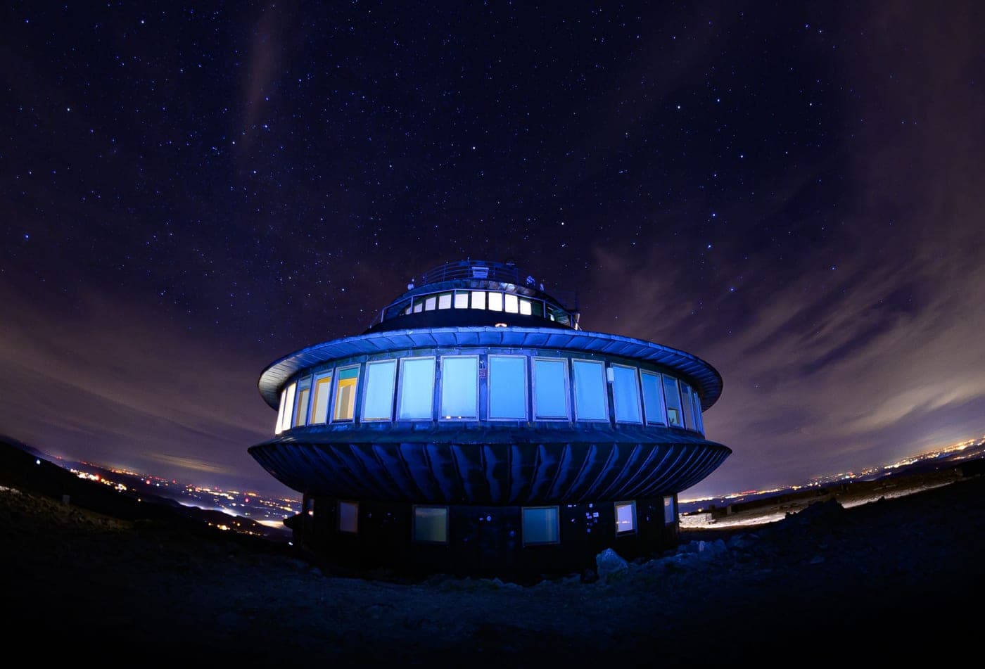 A domed observatory building lit up beneath a starry night sky