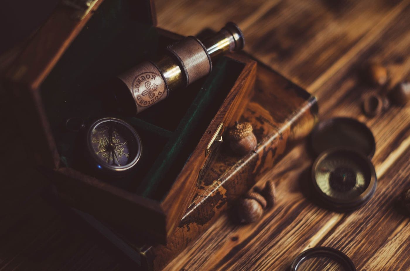 A small telescope and a compass in a wooden box on a rustic table