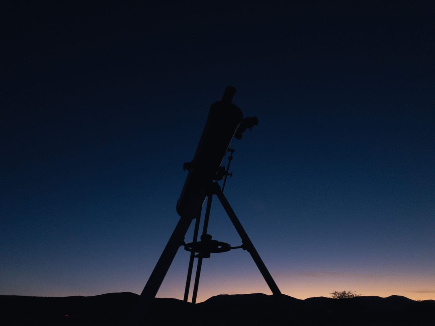 A telescope silhouetted against a twilight sky