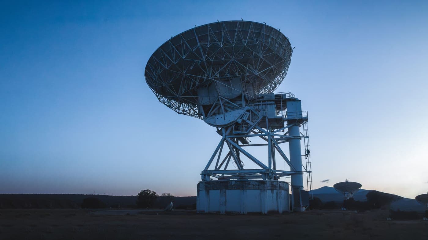 A large dish telescope under a clear evening sky