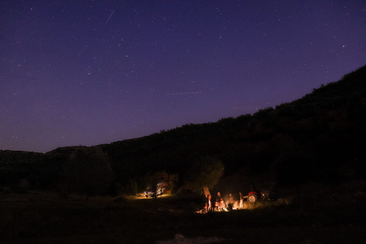 A group gathered around a campfire under a starry sky