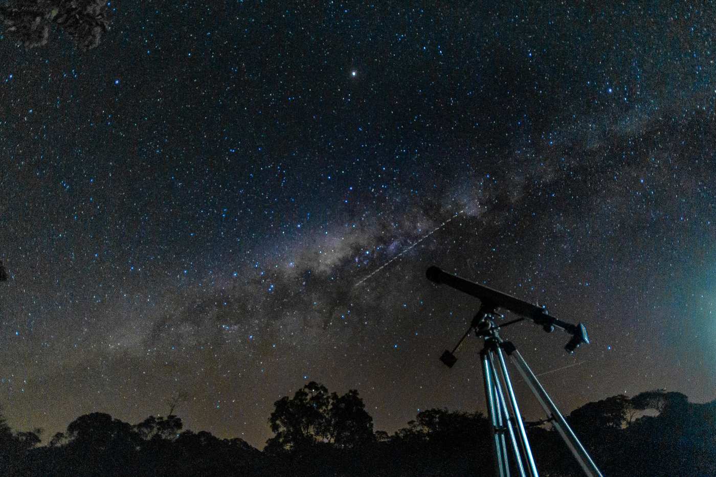 A telescope silhouetted against the Milky Way on a clear night