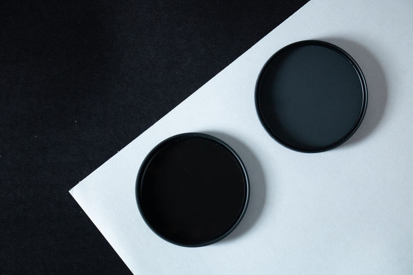 Two black circular optical filters on a plain background