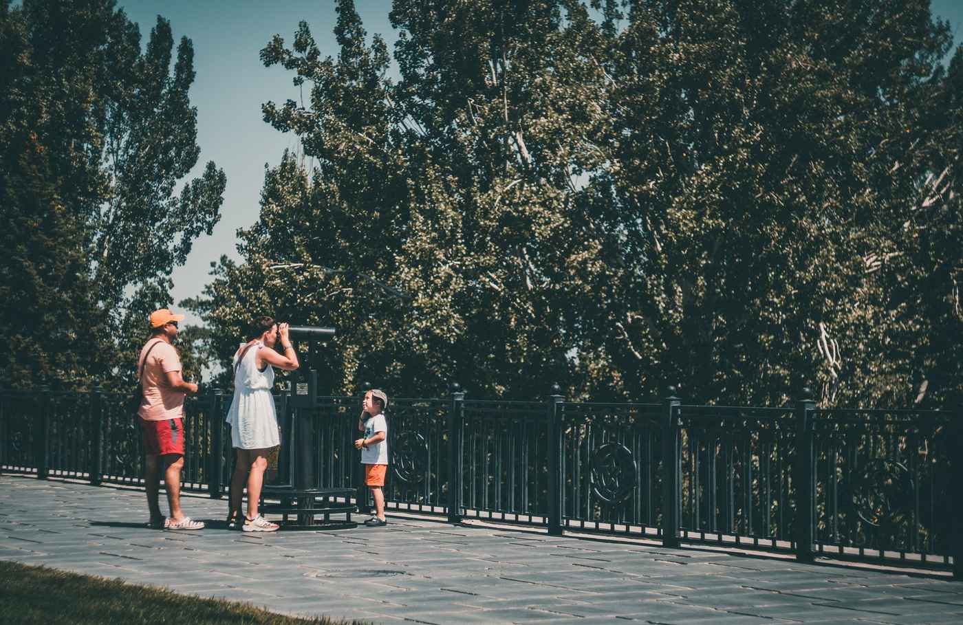 A family with a child using a telescope together in a park
