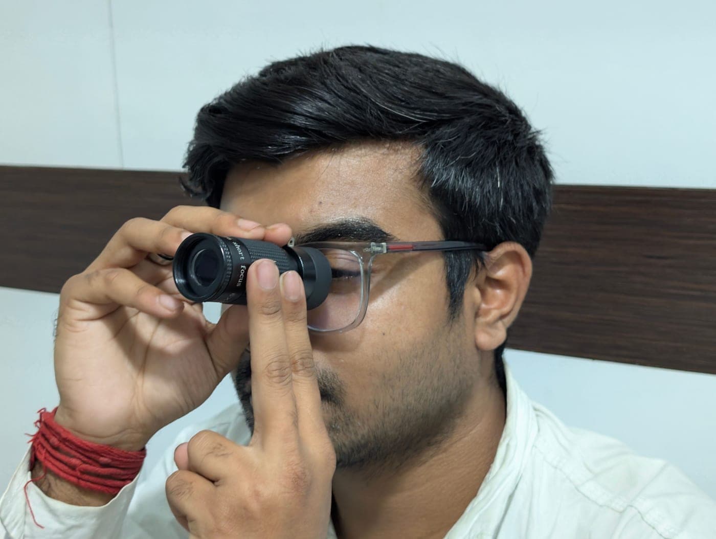 A man examining a small handheld telescope indoors