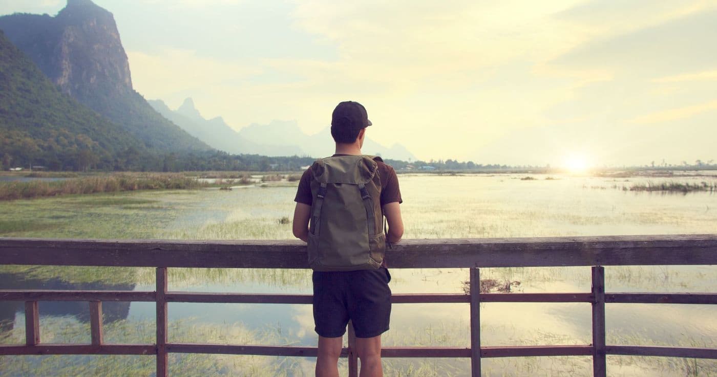 A backpacker looking out over a mountain lake at sunset