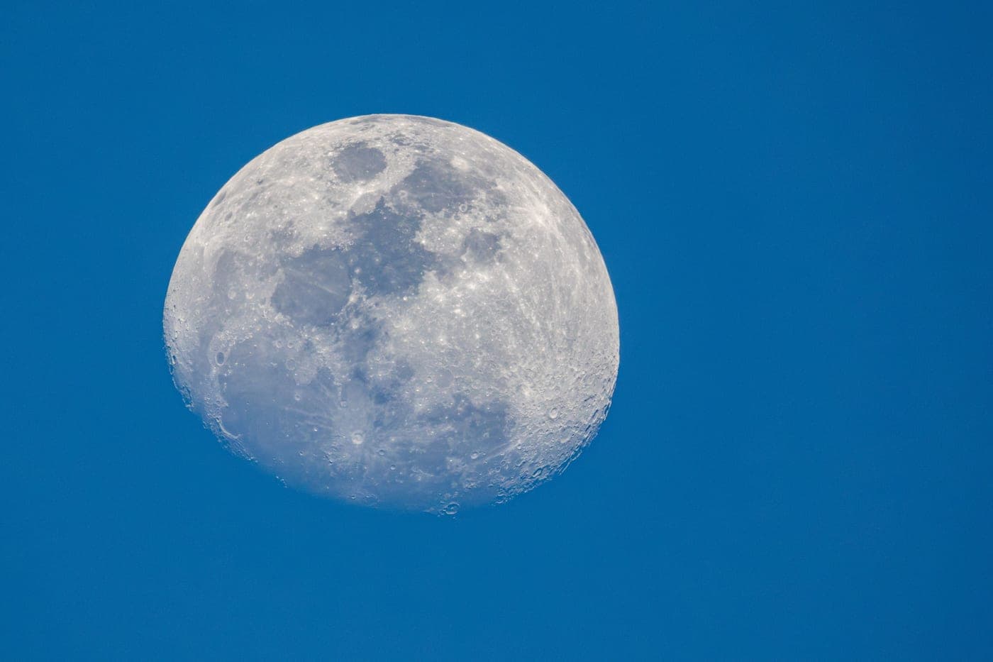 The Moon photographed against a bright blue daytime sky