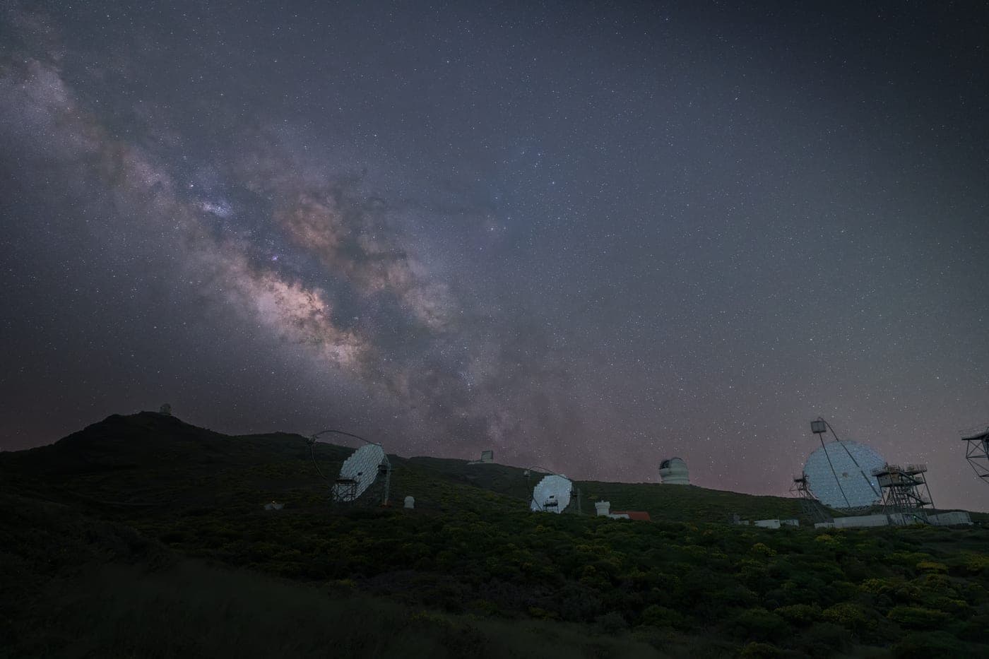 Telescopes on a mountain ridge beneath the Milky Way