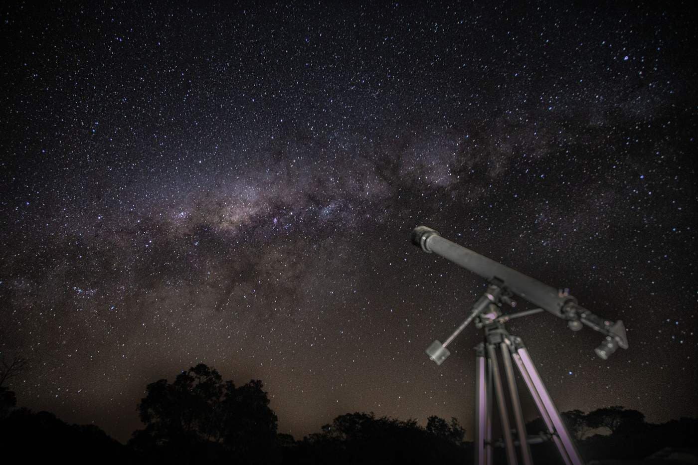 A telescope pointed at a starry night sky showing the Milky Way