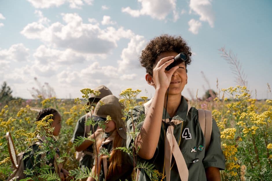 A group observing through a spotting scope in a summer field