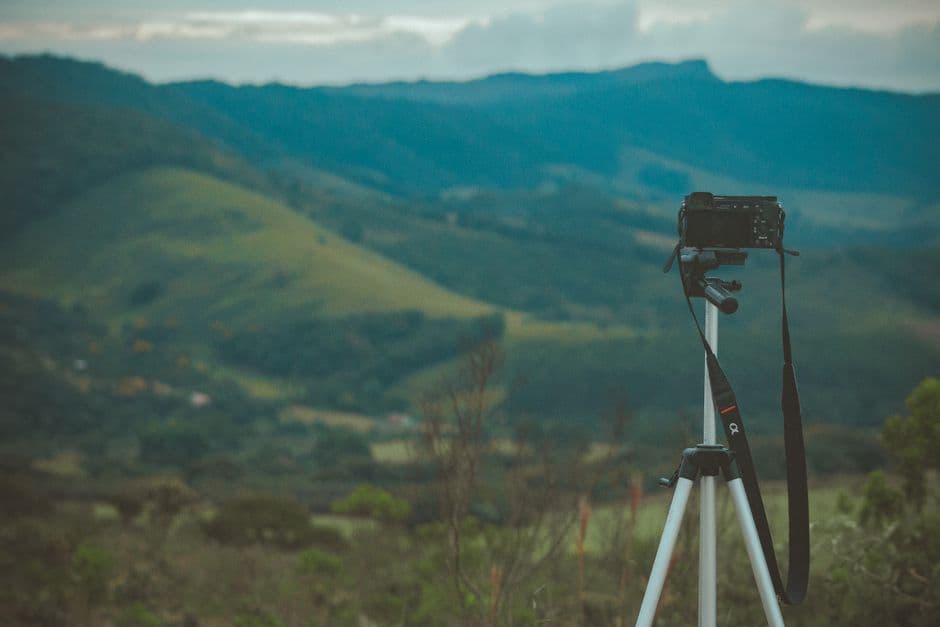 An optic mounted on a tripod framing a mountain landscape at twilight