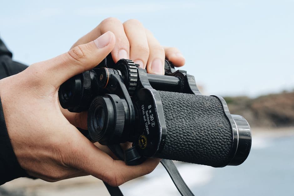 Close-up of hands holding a pair of binoculars outdoors
