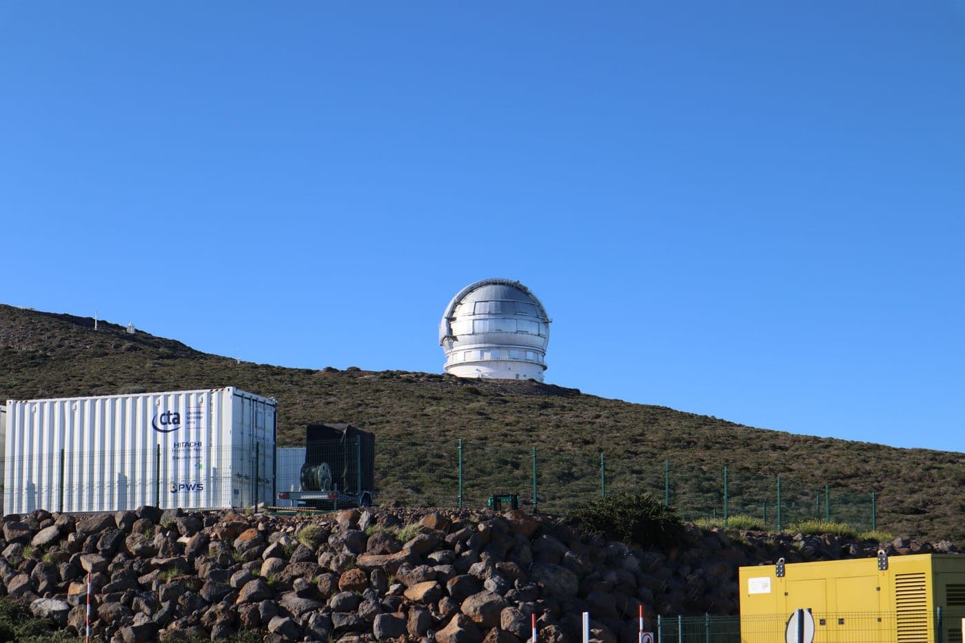 An observatory dome on a hillside under a clear blue sky