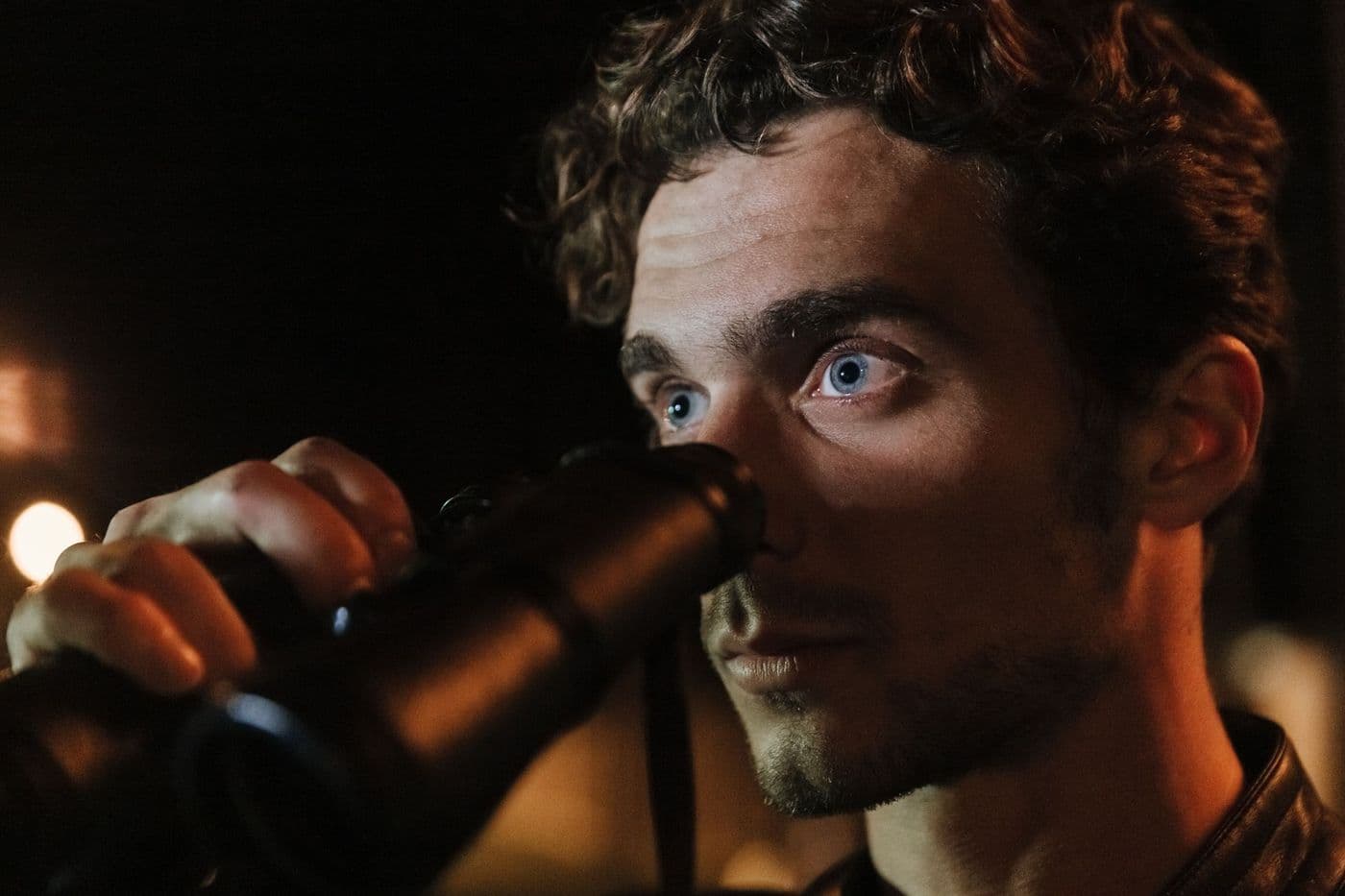 A person using binoculars to observe the sky at night