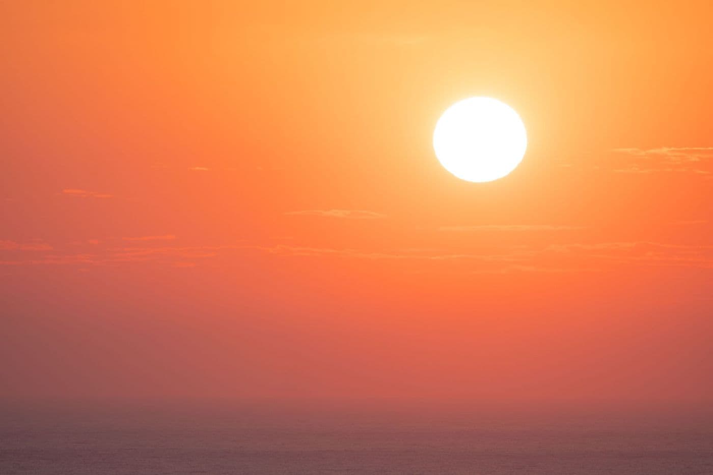 The setting Sun casting orange light across a calm ocean
