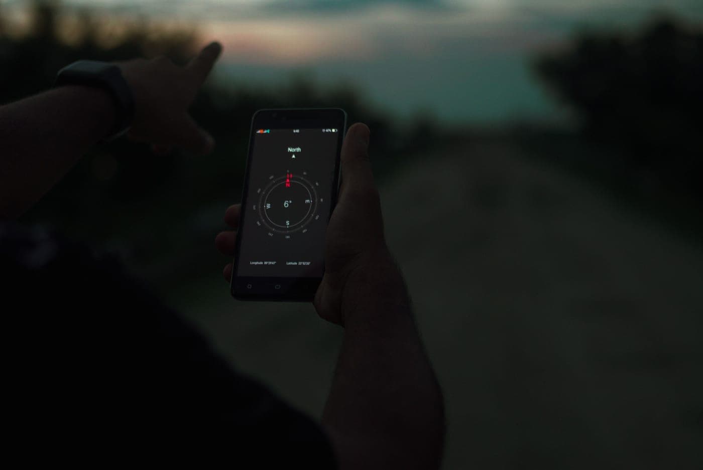 A person holding up a smartphone outdoors at twilight