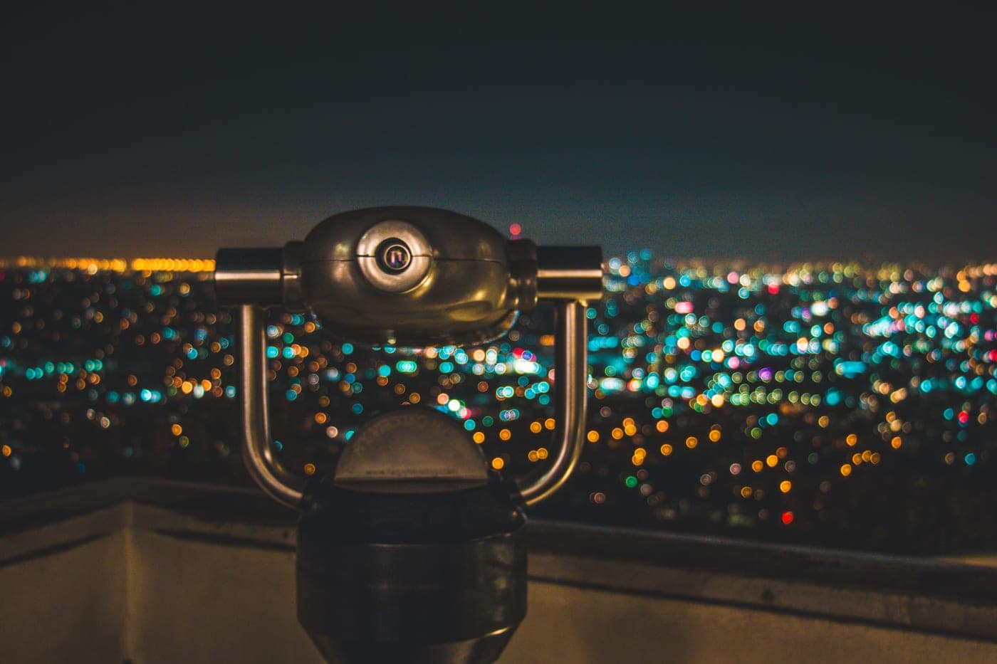 A view through mounted viewing binoculars overlooking a city at dusk