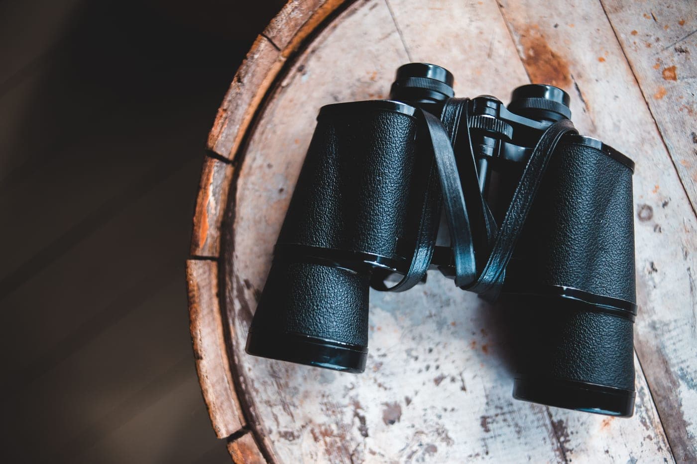 Antique binoculars resting on a rustic wooden table