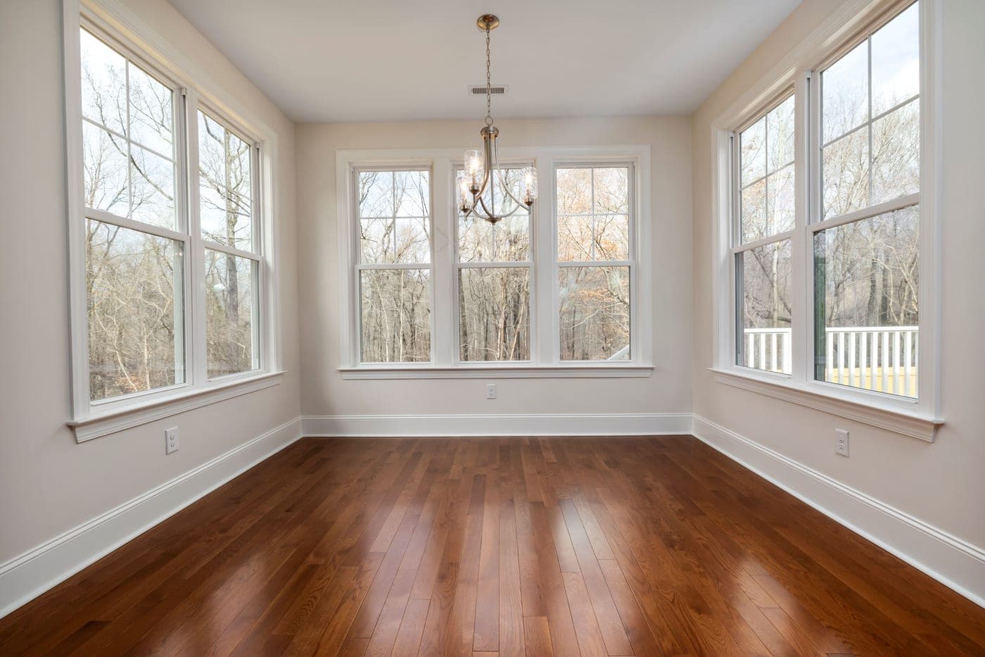 An empty room with large windows and bare wooden floor